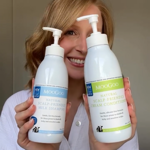 MooGoo Scalp-Friendly Shampoo and Conditioner duo displayed by woman indoors, scalp-soothing SLS-free formula for itchy, flaky scalps.